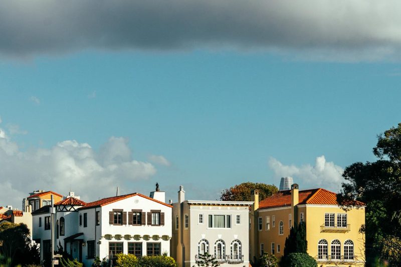 Vibrant Mediterranean-style homes line a street under a cloudy San Francisco sky.