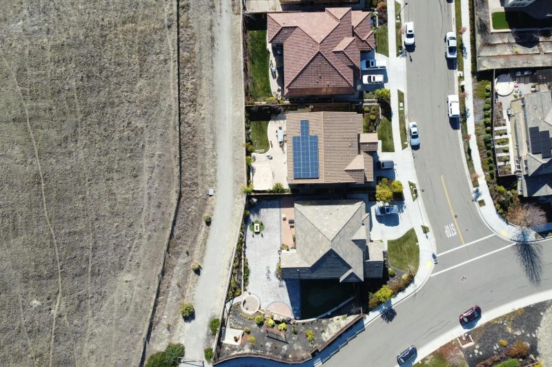 Aerial view of a suburban neighborhood in Dublin, California, featuring homes, solar panels, and parked cars.