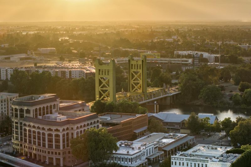 Aerial view of Sacramento's Tower Bridge against a vibrant sunset, showcasing the city's skyline.