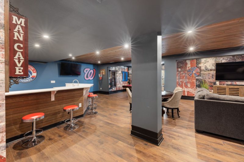 Modern man cave featuring a sleek bar, sports decor, and inviting seating arrangement.