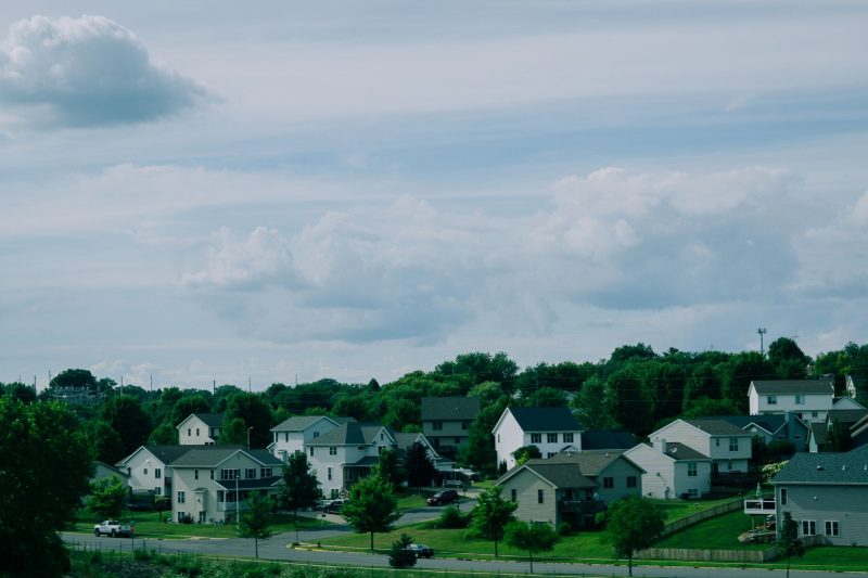 Picturesque suburban houses with green lawns under a blue sky and fluffy white clouds in Wisconsin.