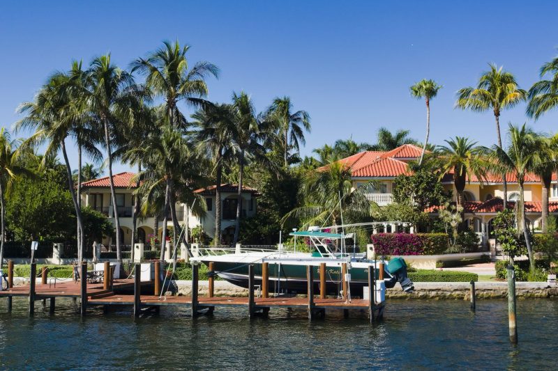 Luxury waterfront homes with palm trees and a docked boat in Fort Lauderdale, Florida.