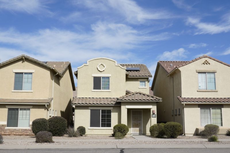 Three adjacent suburban houses in Tucson, Arizona under a clear blue sky.