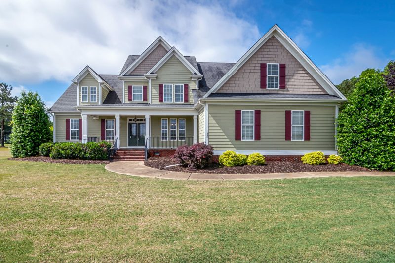 Two-story suburban house with a manicured lawn and inviting front porch.
