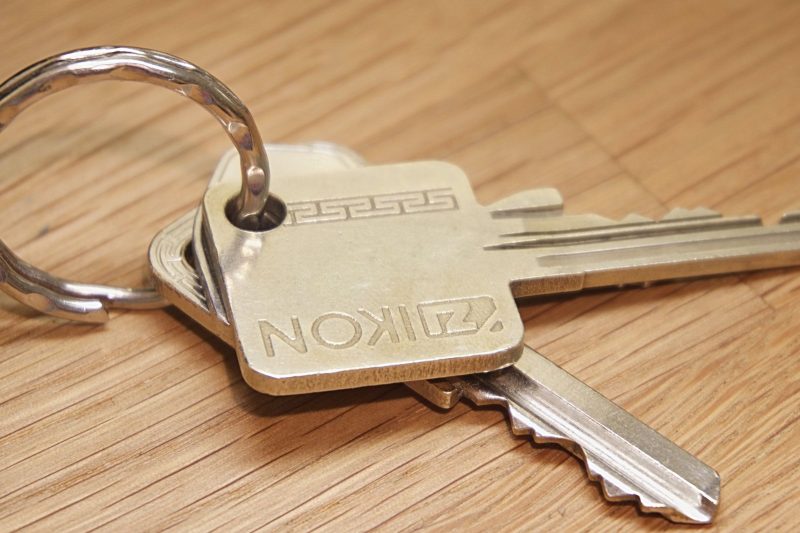 Metal house keys resting on a wooden surface, showcasing a simple, rustic setting.