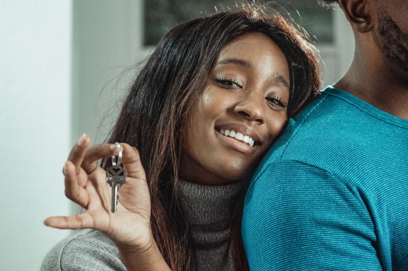 Joyful couple celebrating their new home, proudly holding up a set of house keys.