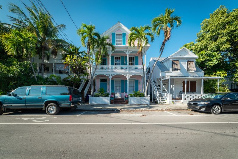 Colorful historic houses and palm trees lining a sunny street in Key West, Florida.